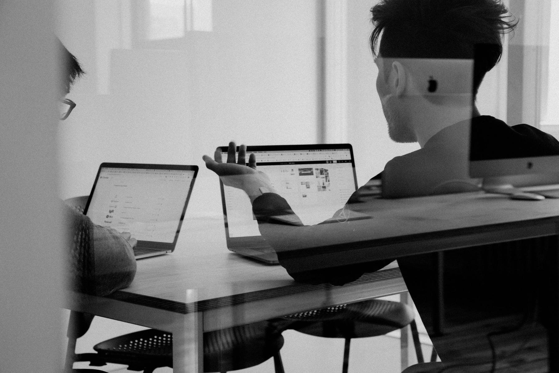 Two people working through a software project at a shared desk